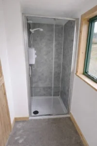 Shepherd’s hut shower with light grey stone effect wet wall panels and electric shower