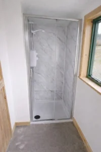 Shepherd’s hut shower with black marble white effect wet wall panels and electric shower