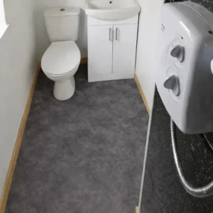 Shepherd’s hut bathroom with custom lino flooring, toilet, sink unit and electric shower