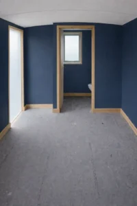 Shepherd’s hut interior with deep blue wall finish, timber trim and partitioned bathroom layout