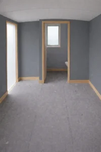 Shepherd’s hut interior with grey wall finish, timber trim and partitioned bathroom layout