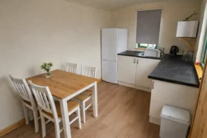 Shepherd’s hut kitchen and dining area with table, fridge and sink