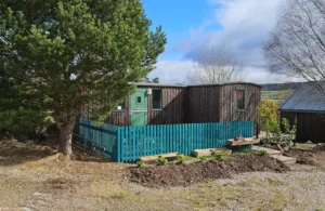 Handcrafted shepherd’s hut with timber cladding and green door in the Scottish Highlands