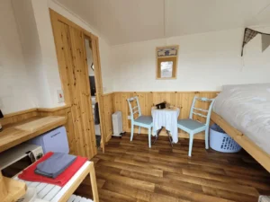 Shepherd’s hut interior with seating area, bed and timber finishes