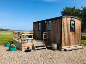 Shepherd’s hut exterior with timber cladding and raised decking area in rural setting
