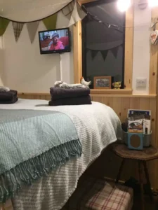 Shepherd’s hut bedroom interior with double bed, window and cosy furnishings