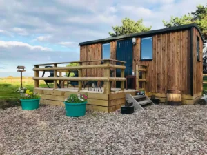 Shepherd’s hut exterior with timber cladding, decking and outdoor seating area
