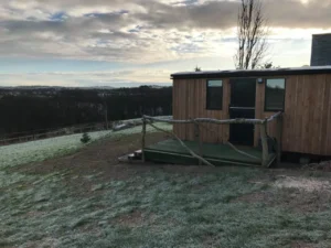 Shepherd’s hut exterior with timber cladding and decking in frosty rural landscape