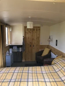Shepherd’s hut interior with double bed, seating area and storage unit