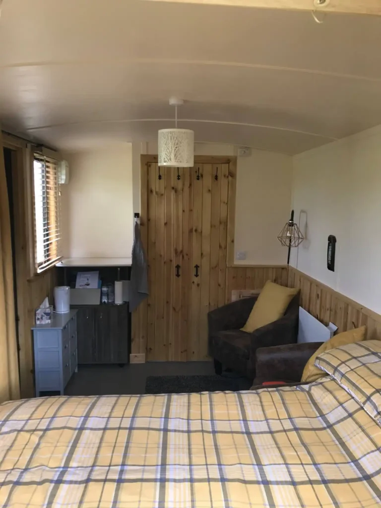 Shepherd’s hut interior with double bed, seating area and storage unit