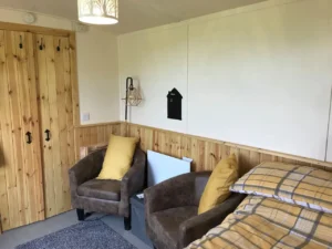 Shepherd’s hut interior with seating area, armchairs and timber wall panelling