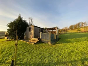 Shepherd’s hut in rural Highland landscape with grass field and surrounding hills