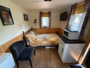 Shepherd’s hut interior with double bed, seating area and kitchenette unit