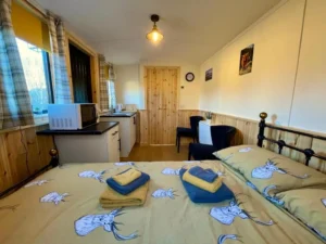 Shepherd’s hut interior with double bed, kitchenette and seating area in compact layout