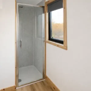 Shower with laminate floor, white walls and shower door