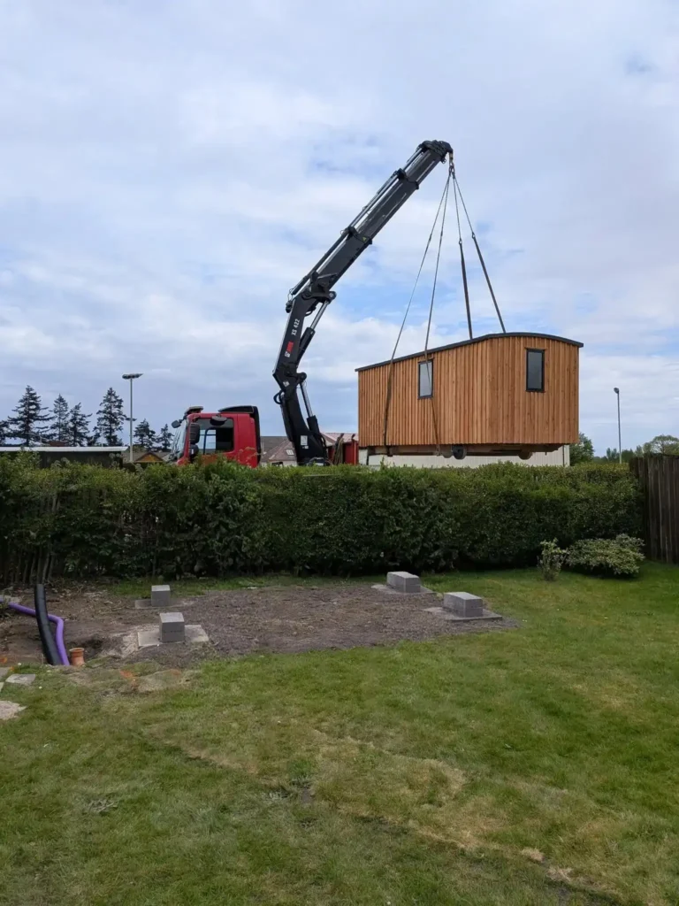 Shepherds hut hiab crane lift over fence